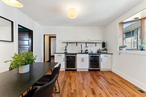 A modern kitchen with white cabinets, a black countertop, and a dining area with a table and chairs.