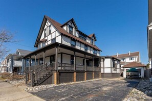 Une maison à deux étages dotée d’un balcon, d’un porche couvert et d’une allée pavée en pierre.