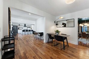 A modern kitchen with white cabinets, a dining area with a table and chairs, and a large mirror on the wall.