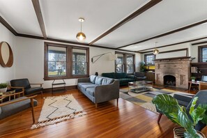 Ein geräumiges Wohnzimmer mit Holzboden, Kamin und großen Fenstern.