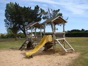 Children can play on the slide and climb the structure in this park setting.