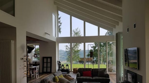 A spacious living room with large windows, a fireplace, and a television.