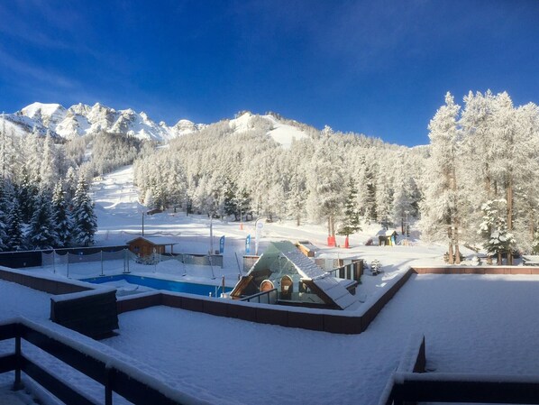 Une station de ski enneigée dotée d’un espace piscine, de chalets et offrant une vue imprenable sur les montagnes.