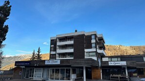 Un edificio moderno de varios pisos con un letrero de estación de esquí, un restaurante y un anuncio de alquiler de ubicación.