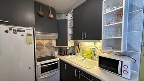 Cocina compacta con refrigerador, horno, microondas y lavaplatos.
