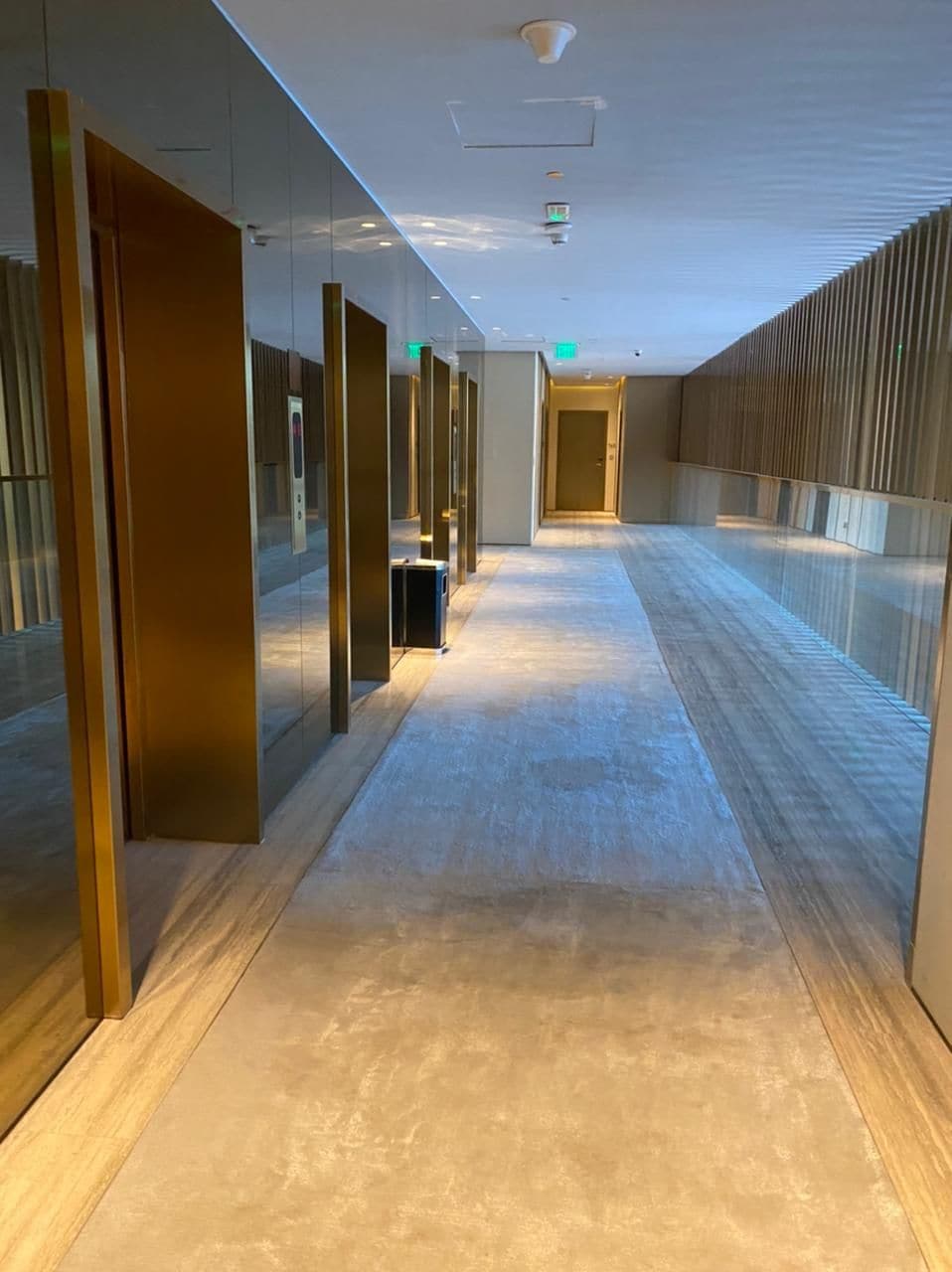 A corridor with glass walls, a bench, and a door at the end.