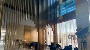 Eine großzügige Lobby mit hoher Decke, moderner Einrichtung und großen Fenstern, die für natürliches Licht sorgen.