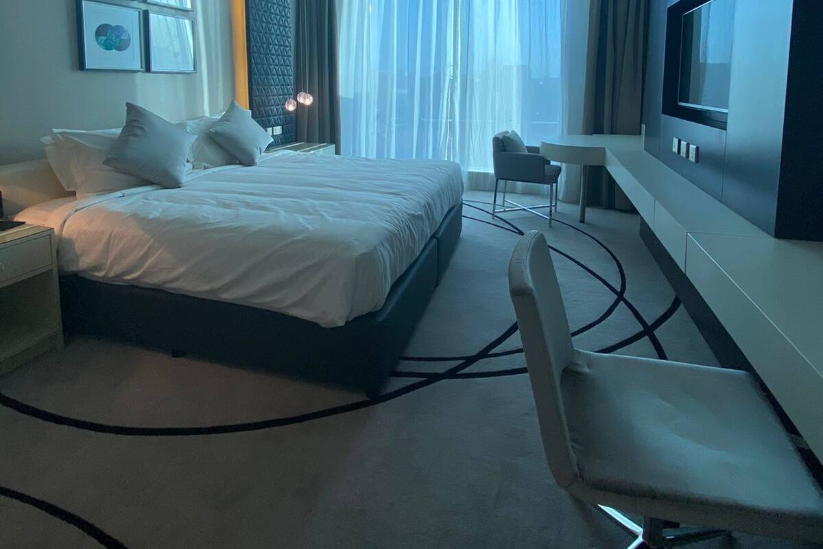 Ein modernes Hotelzimmer mit einem großen Bett, einem Schreibtisch, einem Stuhl, einem Fernseher und einem Fenster mit Vorhängen.