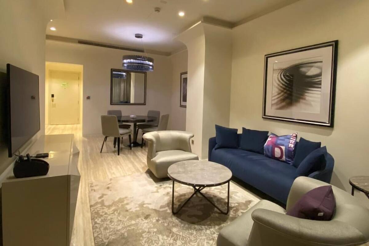 Ein modernes Wohnzimmer mit einer Couch, Sesseln, einem Couchtisch und einem Fernseher.