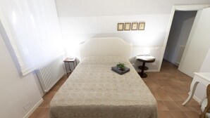 A bedroom with a bed, a bedside table, a radiator, and a window with blinds. - Family room with 2 double or twin rooms near the port and the Venice district. (Livorno)