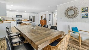 A modern kitchen with white cabinets, a wooden dining table, and black chairs. - Perfect for Projects, Travels, or Transitions (Fernandina Beach)