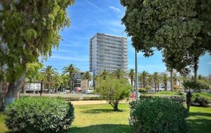 A modern building with multiple floors, surrounded by well-maintained greenery and palm trees. - Seafront Apartment with Wifi in Salou (Salou)