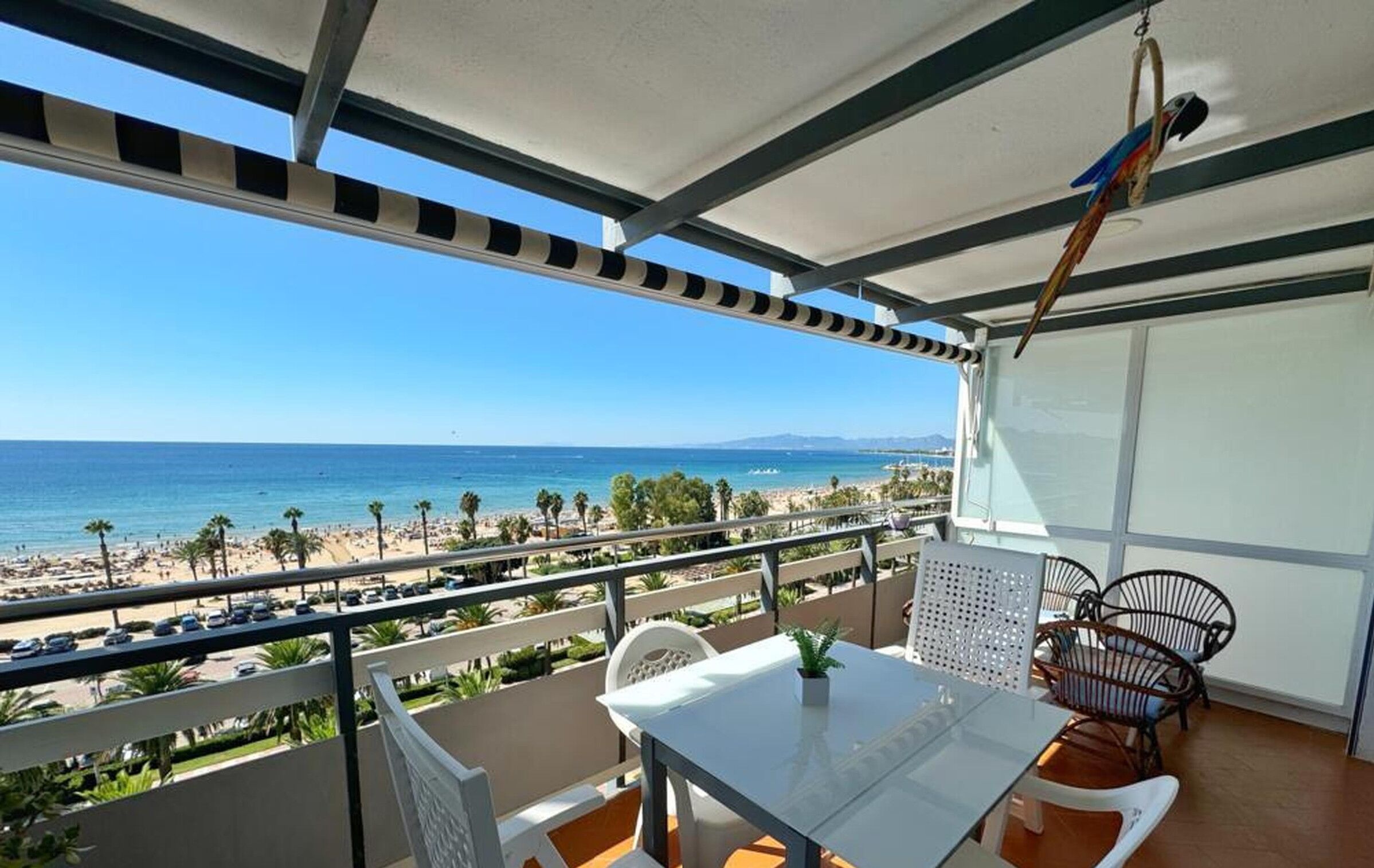 Ein Balkon mit Tisch und Stühlen mit Blick auf einen Strand.