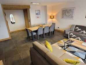 Uma sala de estar moderna com sofá, mesa de centro e área de jantar com mesa e cadeiras.