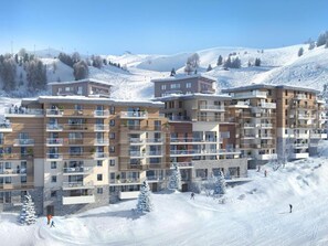Um hotel com várias andares e varandas, com uma paisagem de montanhas nevadas ao fundo.