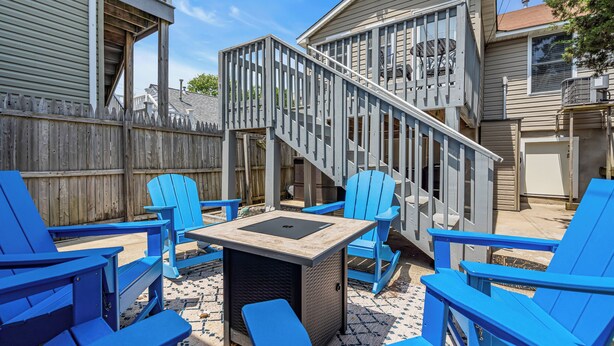 A backyard with blue Adirondack chairs, a small table, and a wooden deck with a staircase. - Professionally Managed | 3 Blocks to Beach (Seaside Heights)