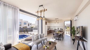 Un apartamento moderno con sala de estar, comedor, cocina y un balcón con piscina.