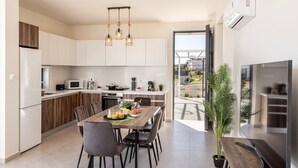 Una cocina moderna con armarios blancos, una mesa de comedor con sillas y un ventanal amplio.
