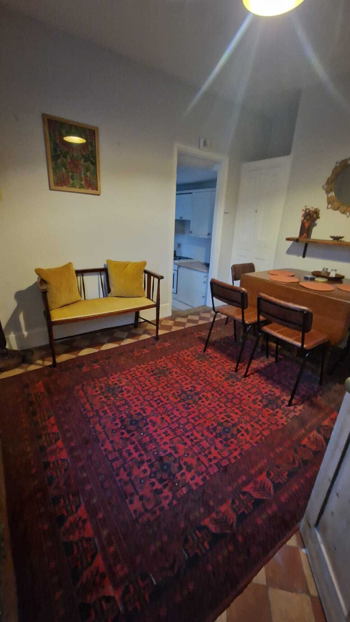 A living room with a sofa, chairs, a dining table, and a patterned rug.