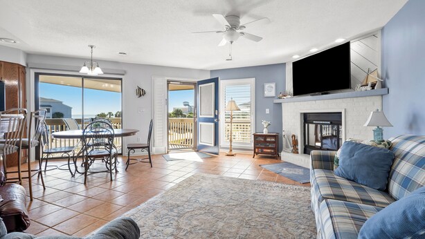 A spacious living area with a large TV, a fireplace, and a balcony with a view. - Tilghman Lakes By the Sea (North Myrtle Beach)