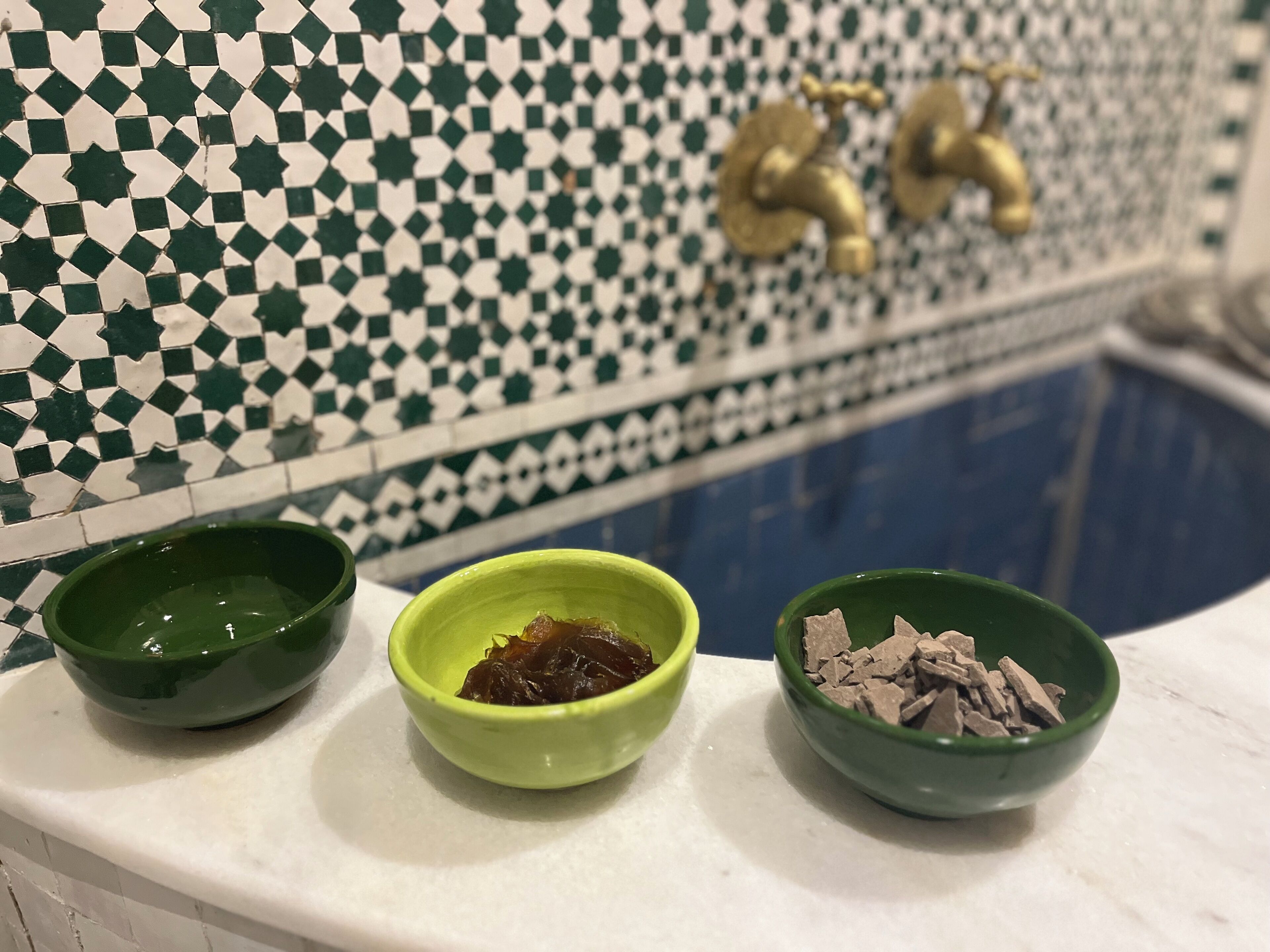 Eine Küchenarbeitsplatte mit drei Schüsseln, die verschiedene Lebensmittel enthalten, einer gefliesten Spritzschutzeinrichtung und einem Wasserhahn.