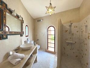 A bathroom with a large mirror, a sink, a vanity, a shower, and a star-shaped light fixture.