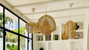 Una habitación con un ventanal grande, un sofá con cojines estampados y estanterías con adornos.