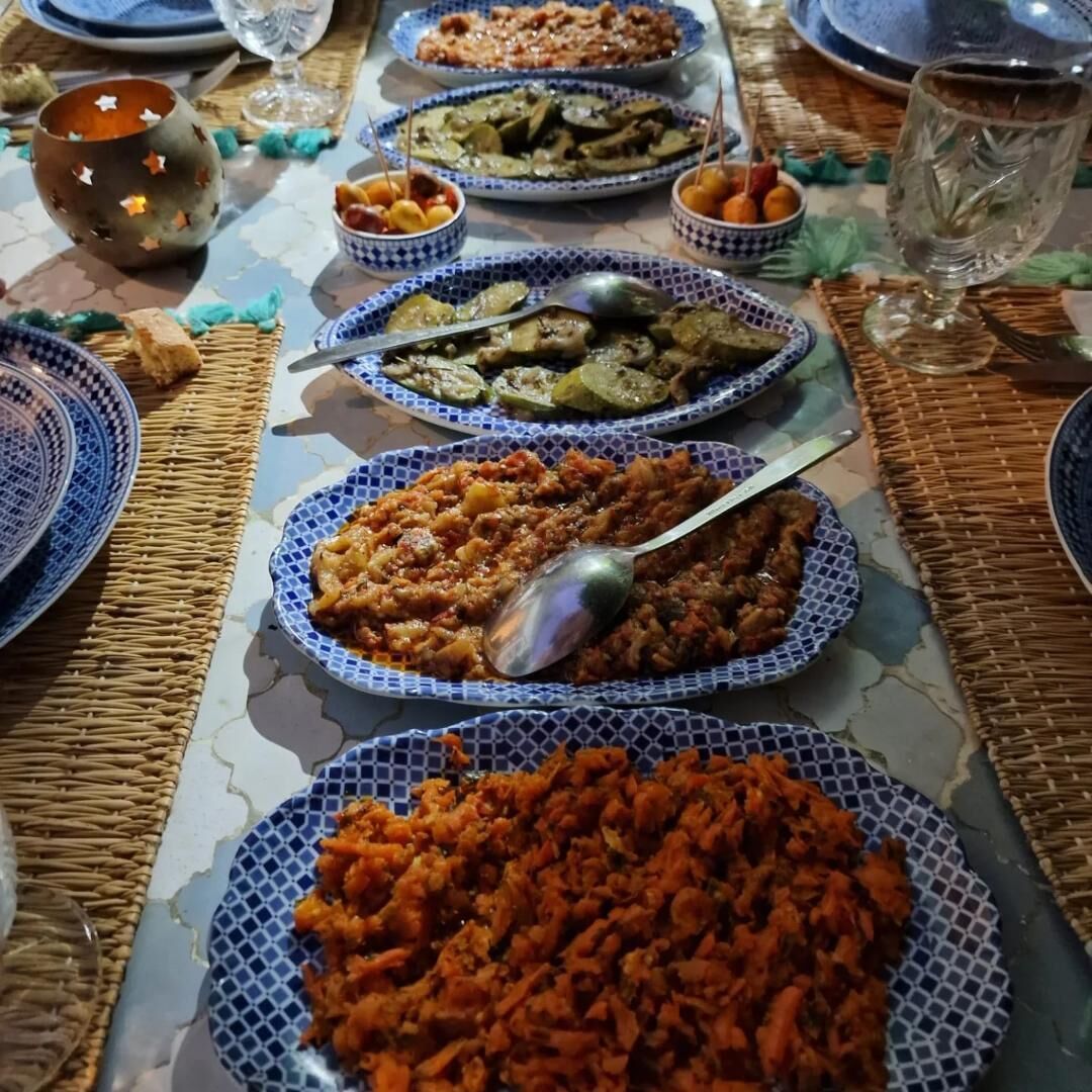 Una mesa dispuesta con diversos platos, incluyendo un plato grande de verduras naranjas, platos más pequeños con diferentes comidas y un cuenco decorativo.