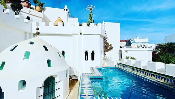 Un edificio blanco con piscina, una cúpula y una estatua en la parte superior.