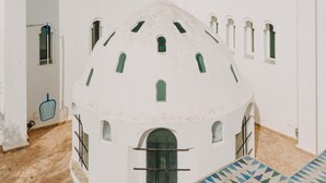 Un edificio blanco con una cúpula, una piscina y palmeras.