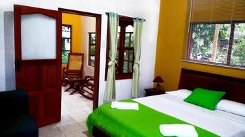 A hotel room with a bed, a chair, a table, and a window with curtains.