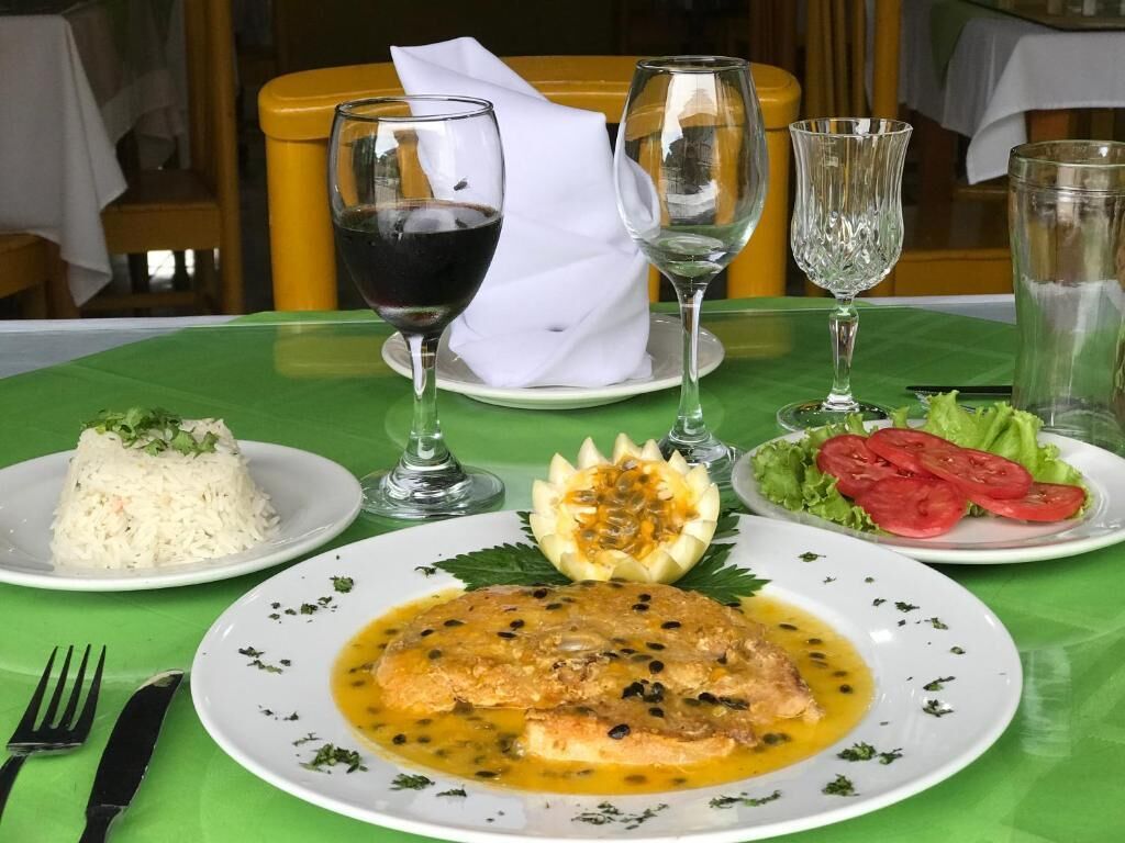 A dining table with a plate of fish, rice, and vegetables, and wine glasses.