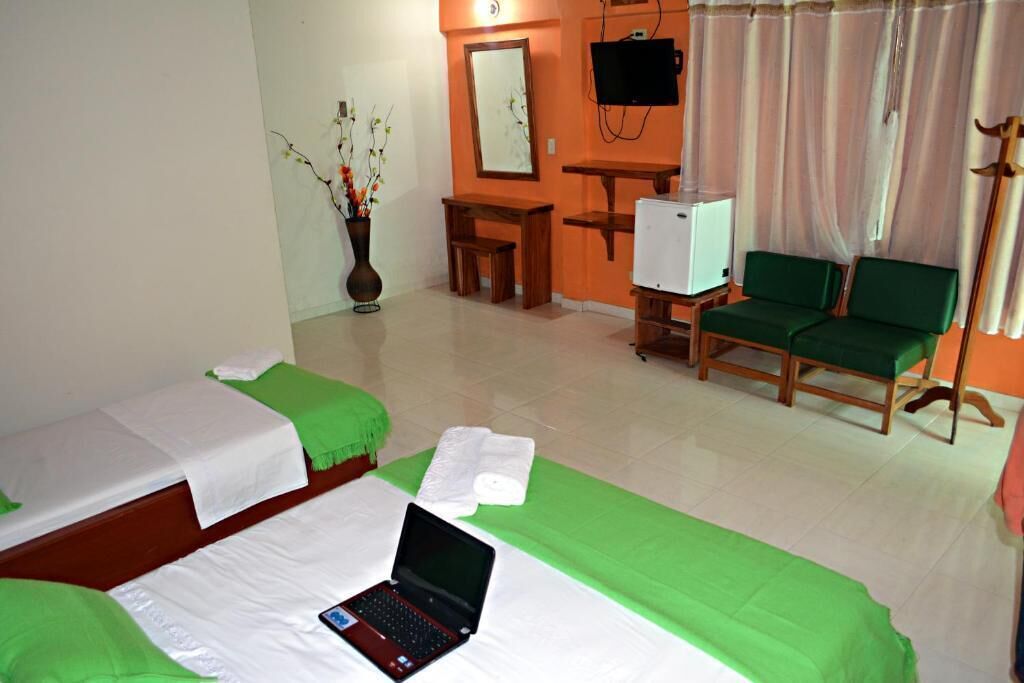 A hotel room with two beds, a desk, a television, and a chair.