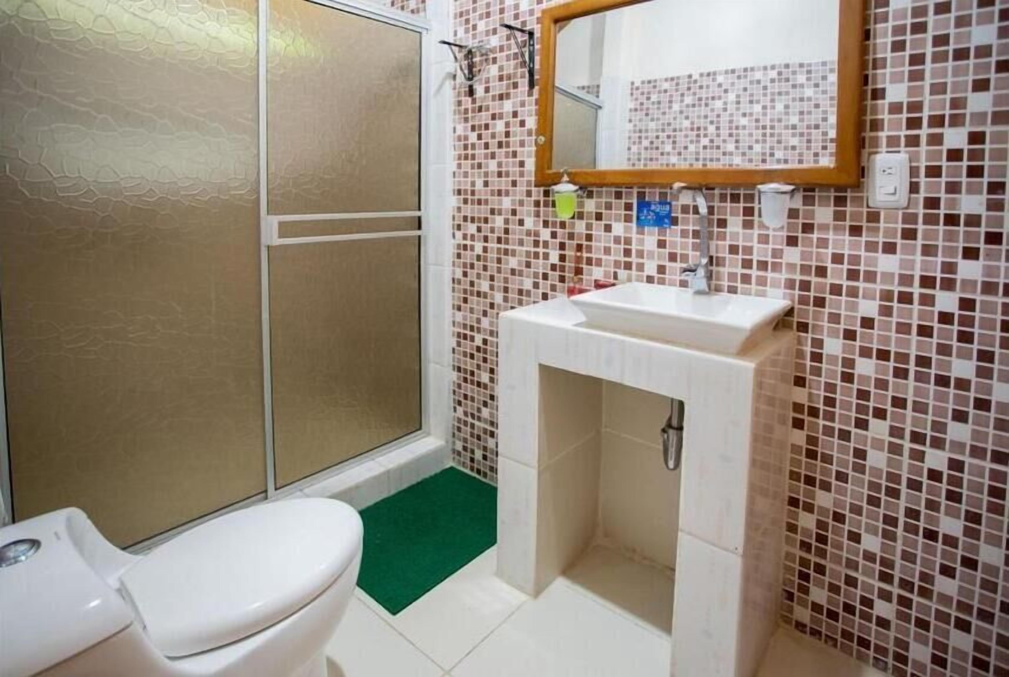 Een badkamer met een toilet, een wastafel en een douche met een glazen deur.