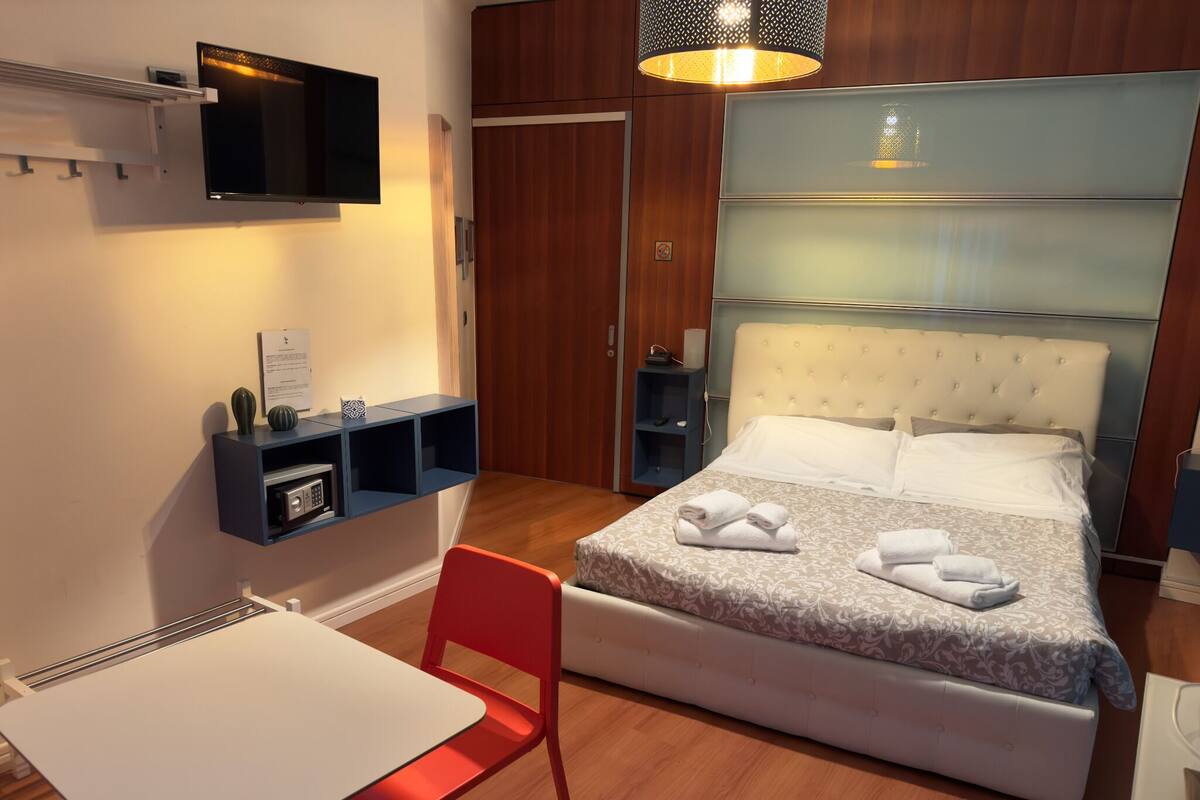 Een hotelkamer met een bed, een bureau, een stoel, een televisie en een kledingkast.