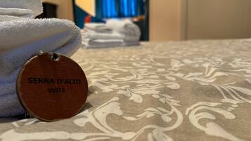A bed with a patterned bedspread and a tag reading "SERRA D'ALTO SUITE".