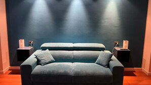 Un salon moderne avec un mur bleu foncé, un canapé bleu clair et deux tables d’appoint avec des lampes.