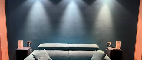 A modern living room with a dark blue wall, a light blue sofa, and two side tables with lamps.