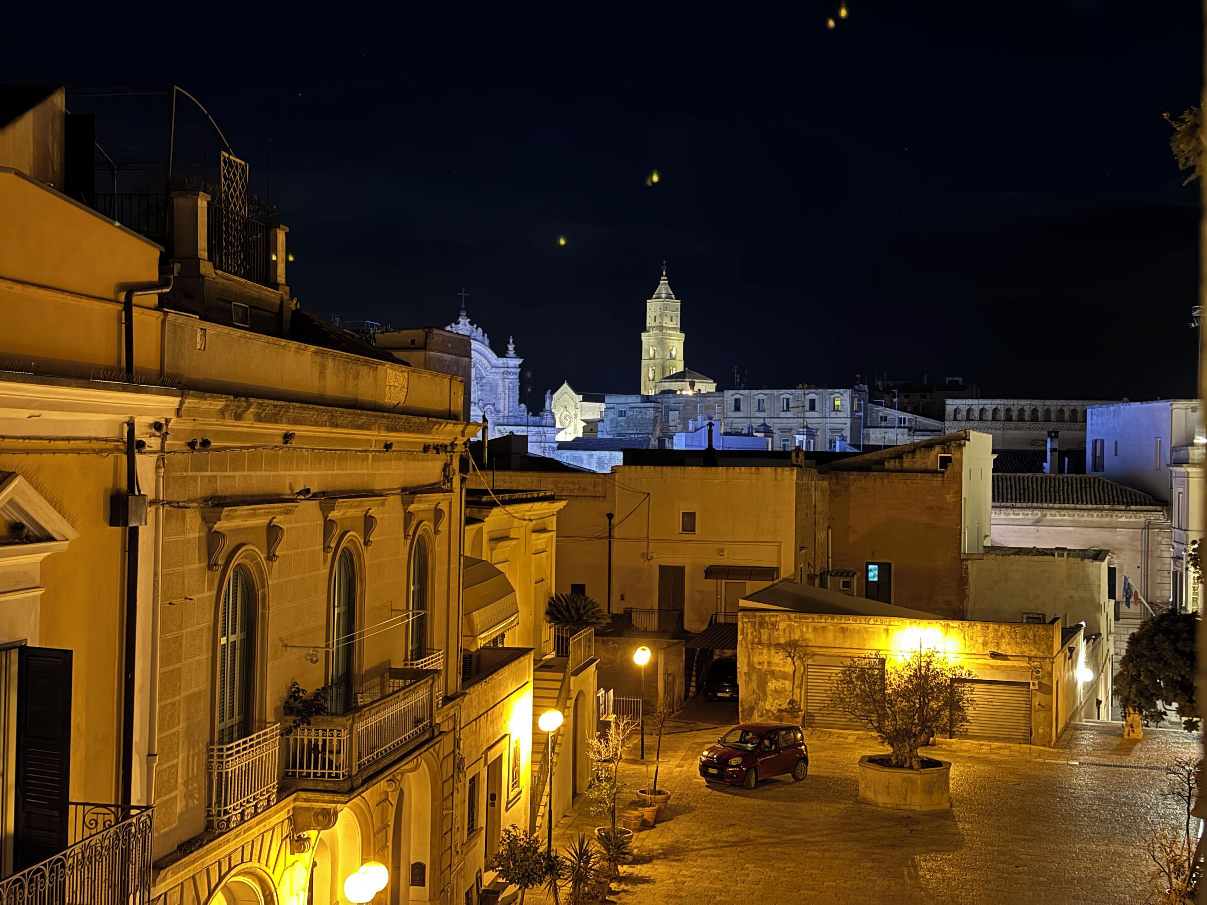 Una vista nocturna de un casco antiguo con una torre destacada y edificios iluminados.