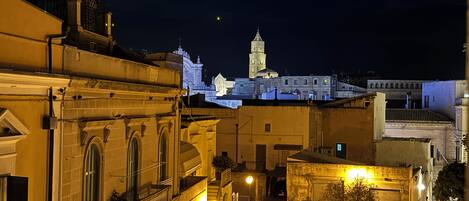 Vista noturna de um centro histórico com uma torre imponente e edifícios iluminados.