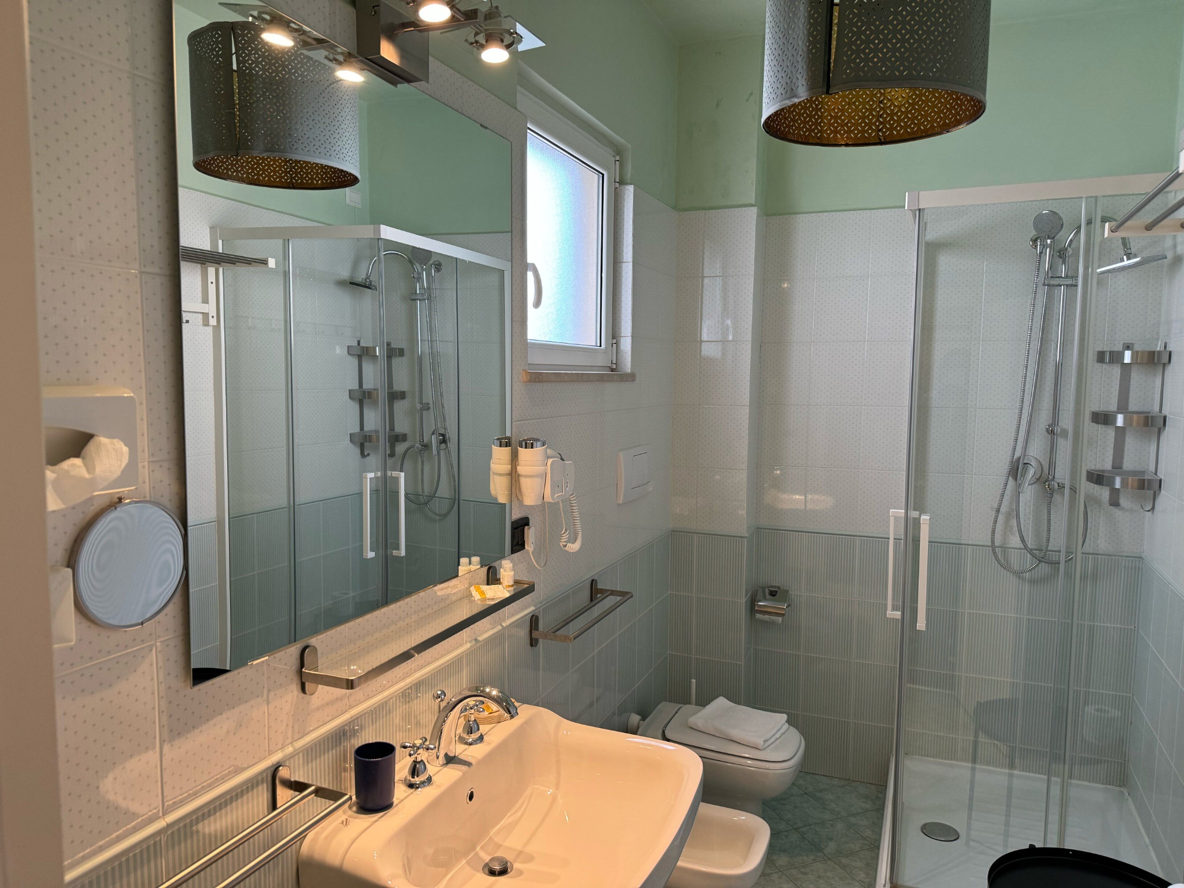 Un baño moderno con ducha de vidrio, lavamanos con espejo y retrete.