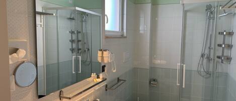 Un baño moderno con ducha de vidrio, lavamanos con espejo y retrete.
