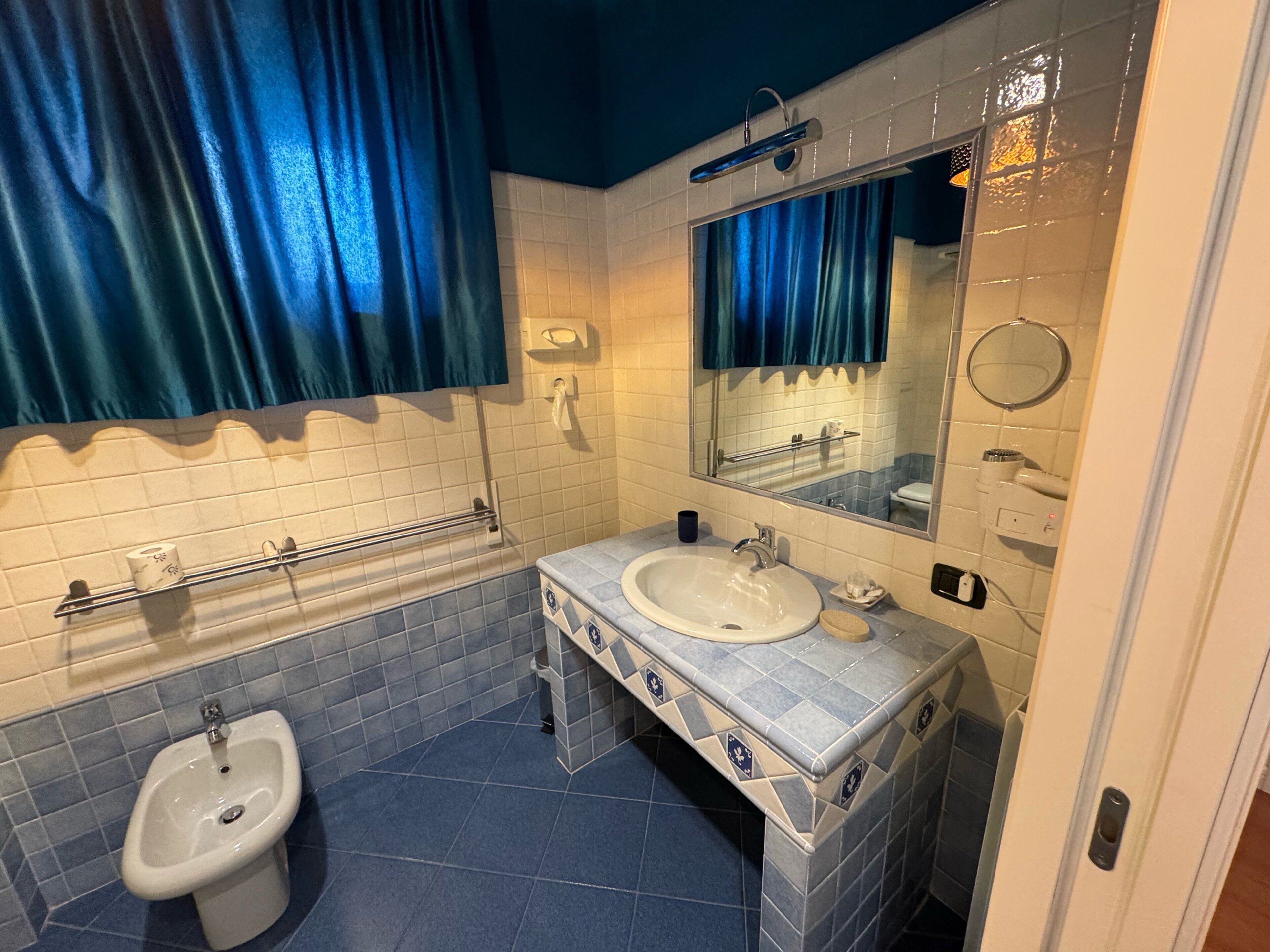 Une salle de bain équipée d’un bidet, d’un lavabo, d’un miroir et d’un porte-serviettes.