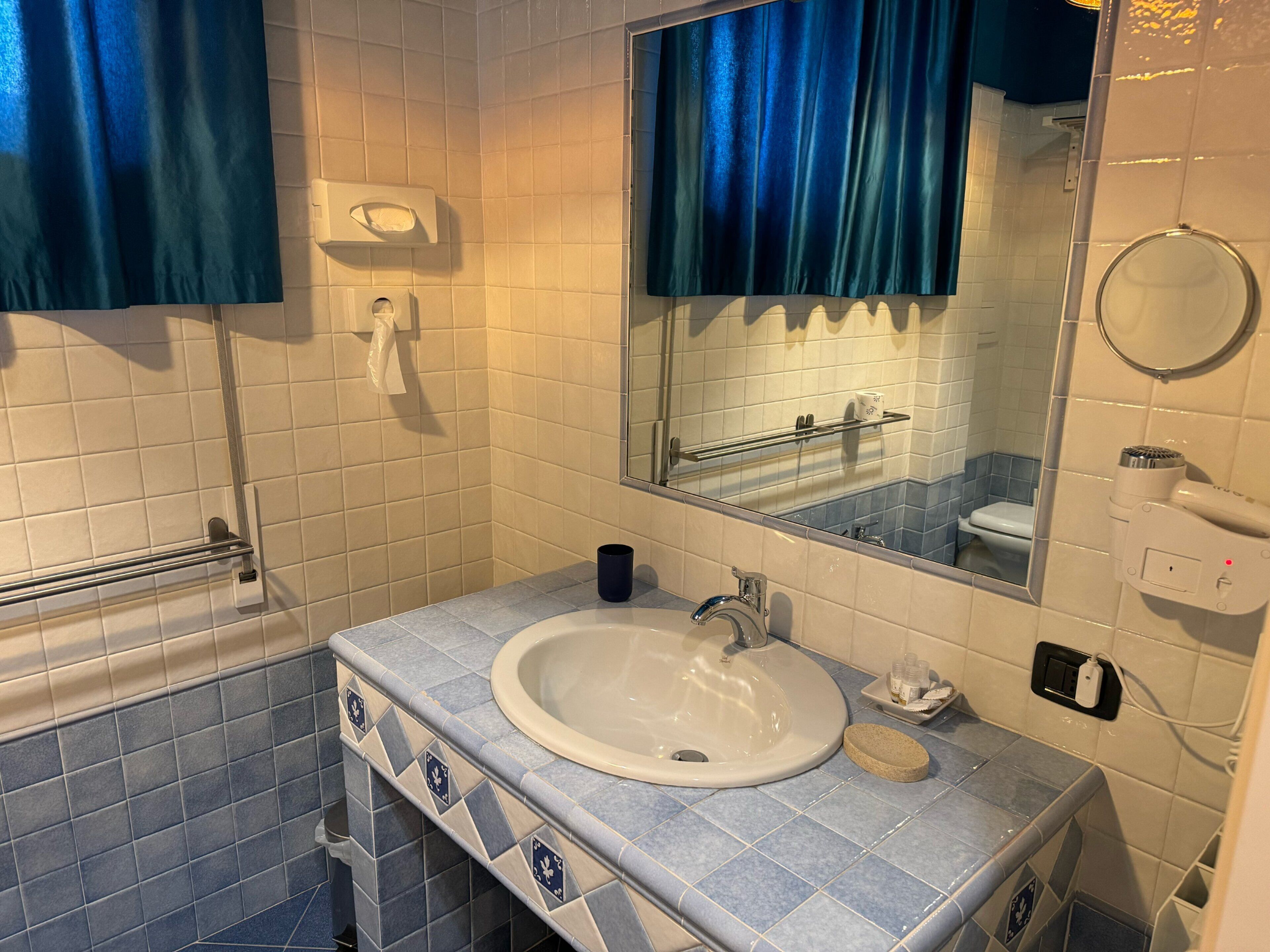 Ein Badezimmer mit Waschbecken, Spiegel, Seifenspender und Duschbereich.