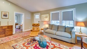 Un salon comprenant un canapé, des fauteuils, une table basse en verre et un tapis à motifs.