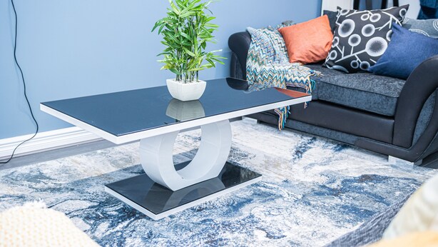 A modern living room with a black coffee table, a potted plant, a grey sofa with patterned cushions, and a blue carpet. - Impeccable 4-bed House in Telford, West Midlands (Telford)
