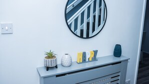 A modern interior with a white wall, a circular mirror, a small potted plant, a decorative vase, and a console table with the word "HAPPY" on it. - Impeccable 4-bed House in Telford, West Midlands (Telford)