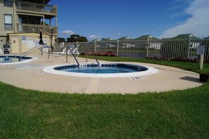 A pool area with a lifeguard stand, lounge chairs, and a fenced pool.