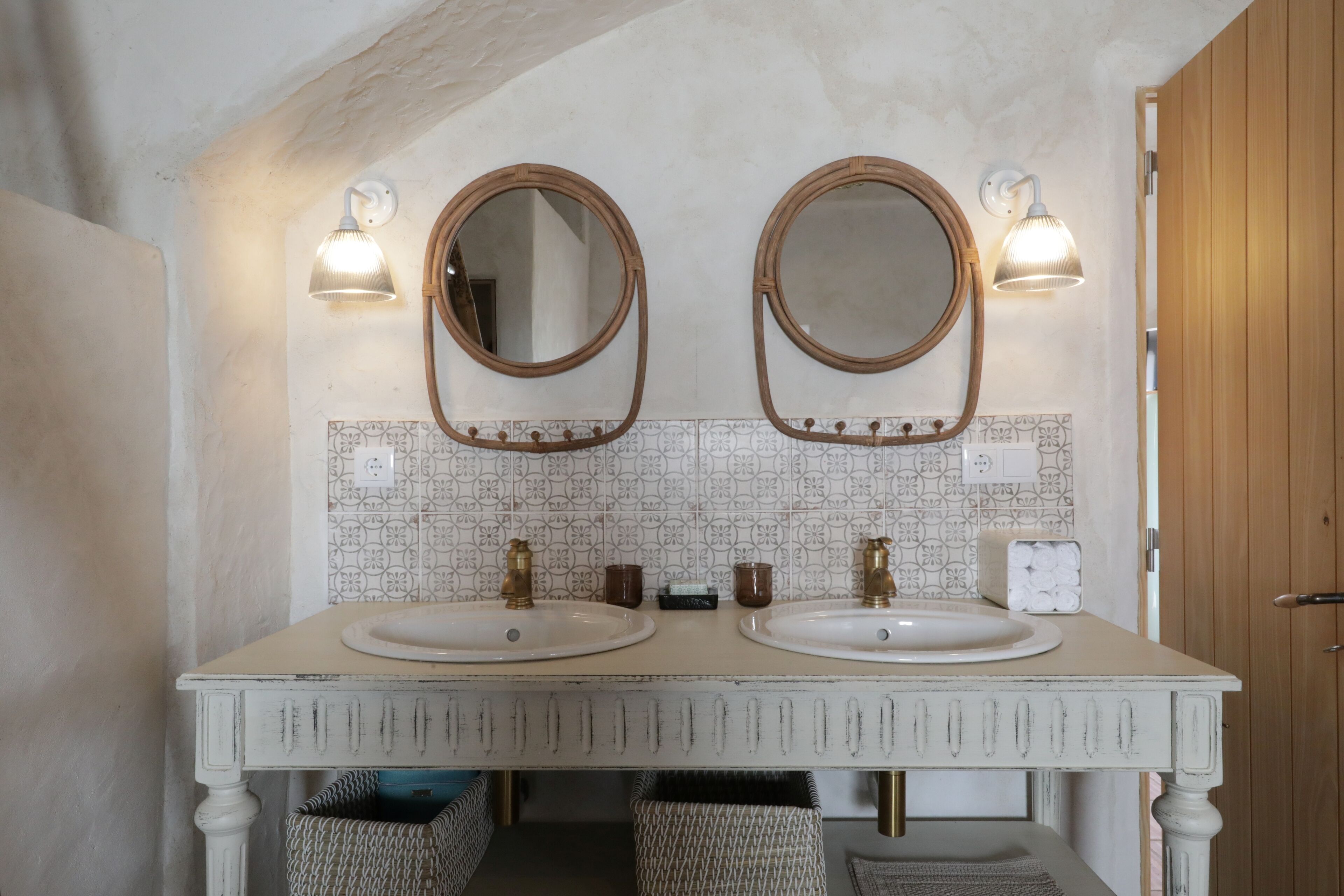 Un baño con dos lavamanos, un espejo y apliques de pared.