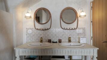 Un baño con dos lavamanos, un espejo y apliques de pared.